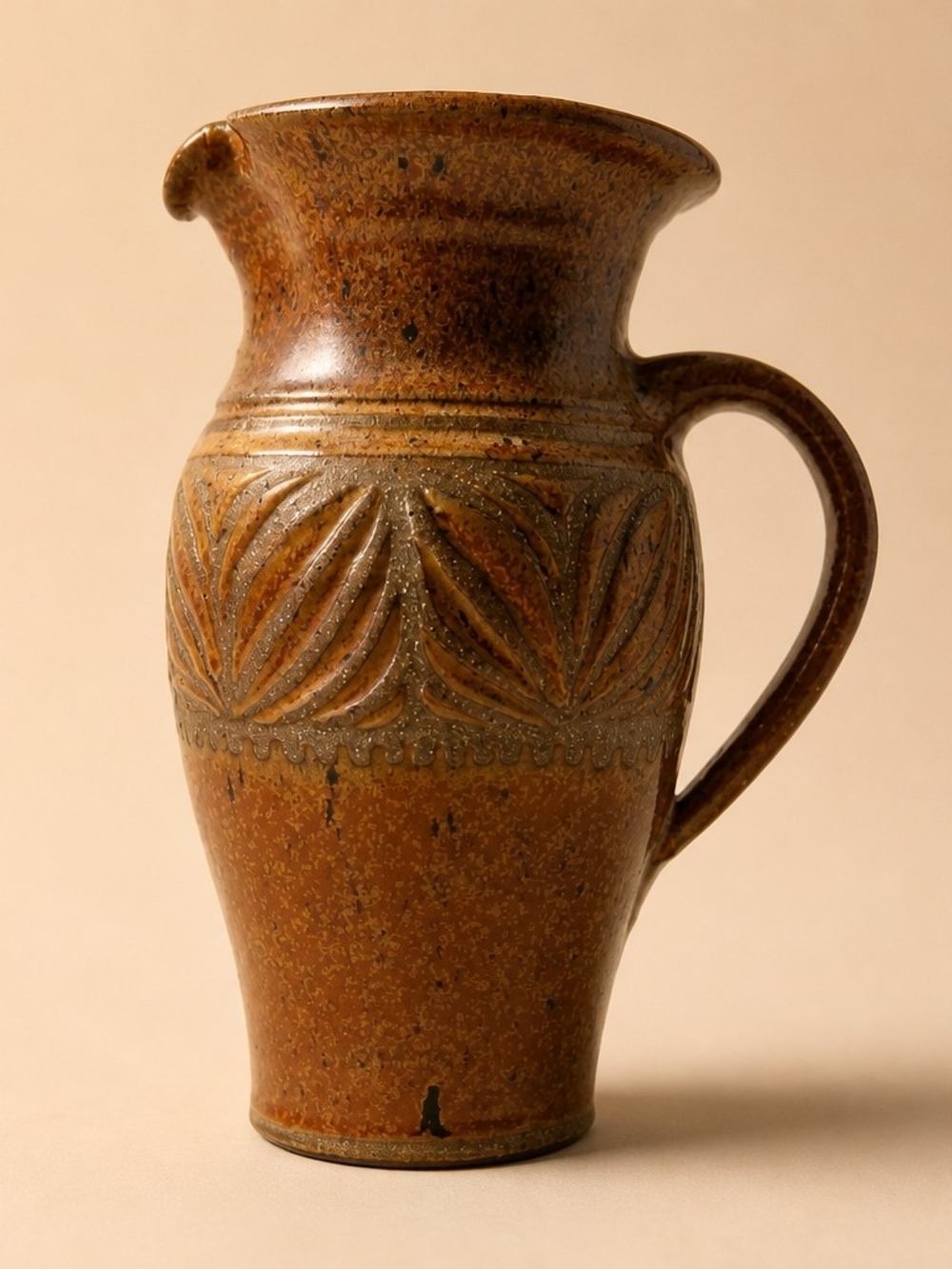 Studio pottery pitcher with incised leaf decoration and a speckled glaze